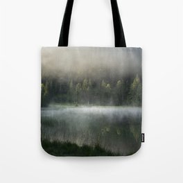 Magic Misty Lake. Amazing shot of a wooden house in the Ferchensee lake in Bavaria, Germany, in front of a mountain belonging to the Alps. Scenic foggy morning scenery at sunrise. Tote Bag